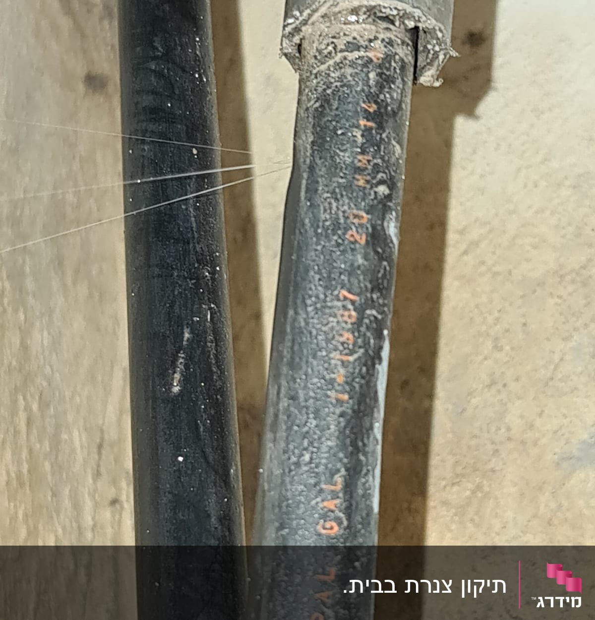 צינור שחור עם כיתוב אדום על רקע קיר